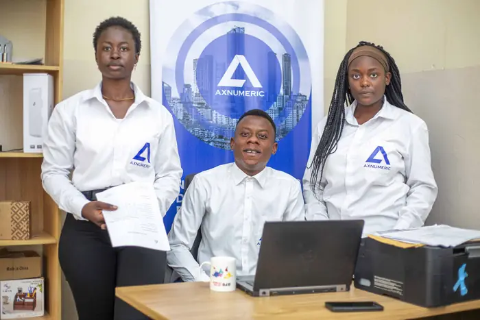 Trois membres de l'équipe AXNUMERIC en chemise à logo, devant la bannière de l'entreprise