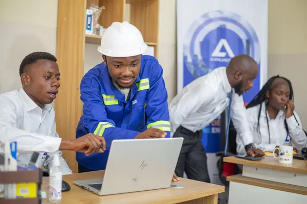 Un technicien en casque et veste bleue montre un écran à ses collègues