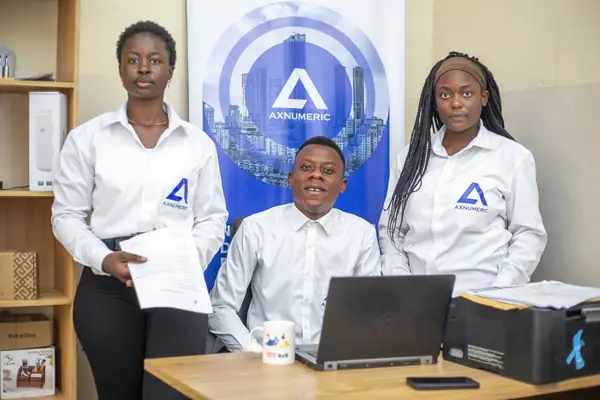 Trois membres de l'équipe en chemise AXNUMERIC posent devant la bannière de l'entreprise