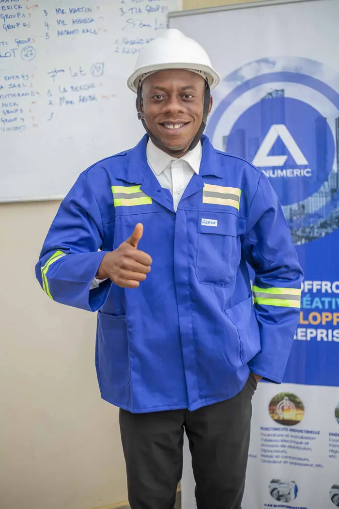 Un technicien d'AXNUMERIC en casque et veste bleue, pouce levé
